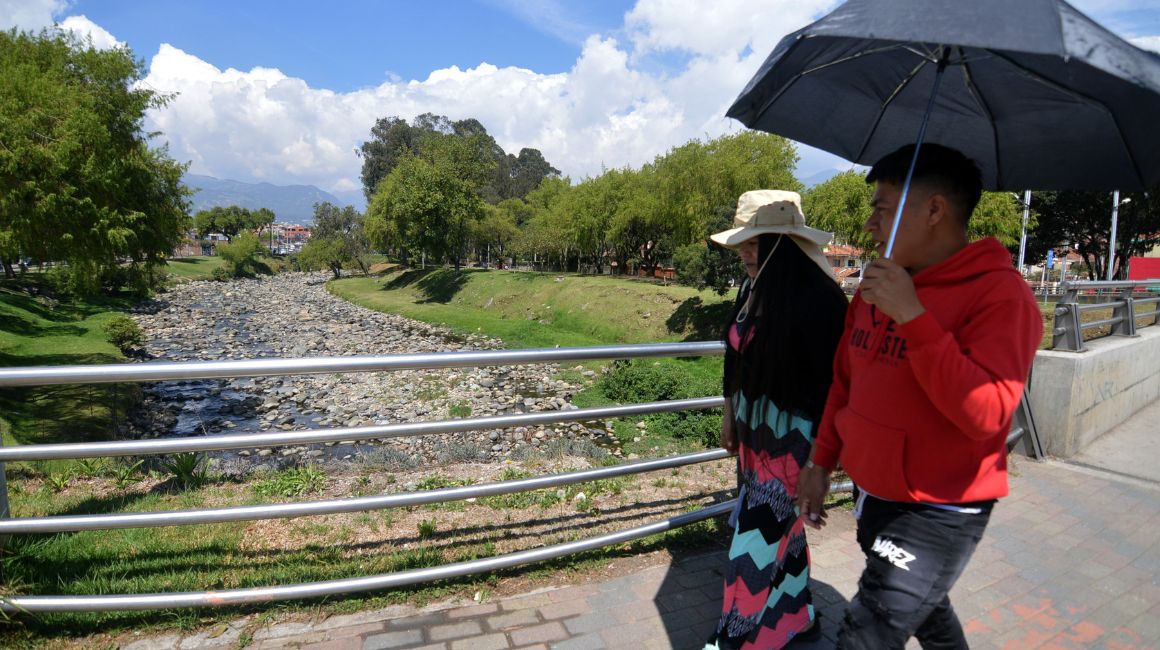 Personas caminan por un puente del río Tomebamba, de Cuenca, durante el estiaje, en noviembre de 2023.