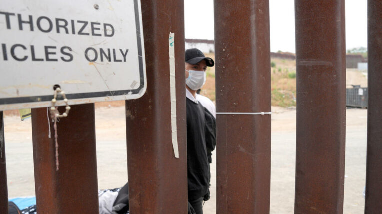 Un migrante espera junto al muro fronterizo, este miércoles en San Ysidro, San Diego, Estados Unidos.