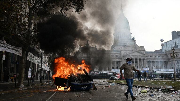 Un manifestante huye de un auto en llamas durante una protesta frente al Congreso Nacional en Buenos Aires el 12 de junio de 2024.
