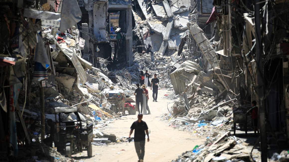 Hombres palestinos caminan por una calle con edificios destruidos en Khan, 11 de junio de 2024.