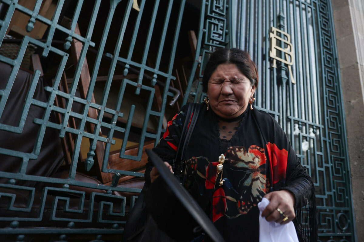 Una mujer se protege de gases durante un movimiento militar frente a la sede del Gobierno de Bolivia, el 26 de junio de 2024, en La Paz (Bolivia).