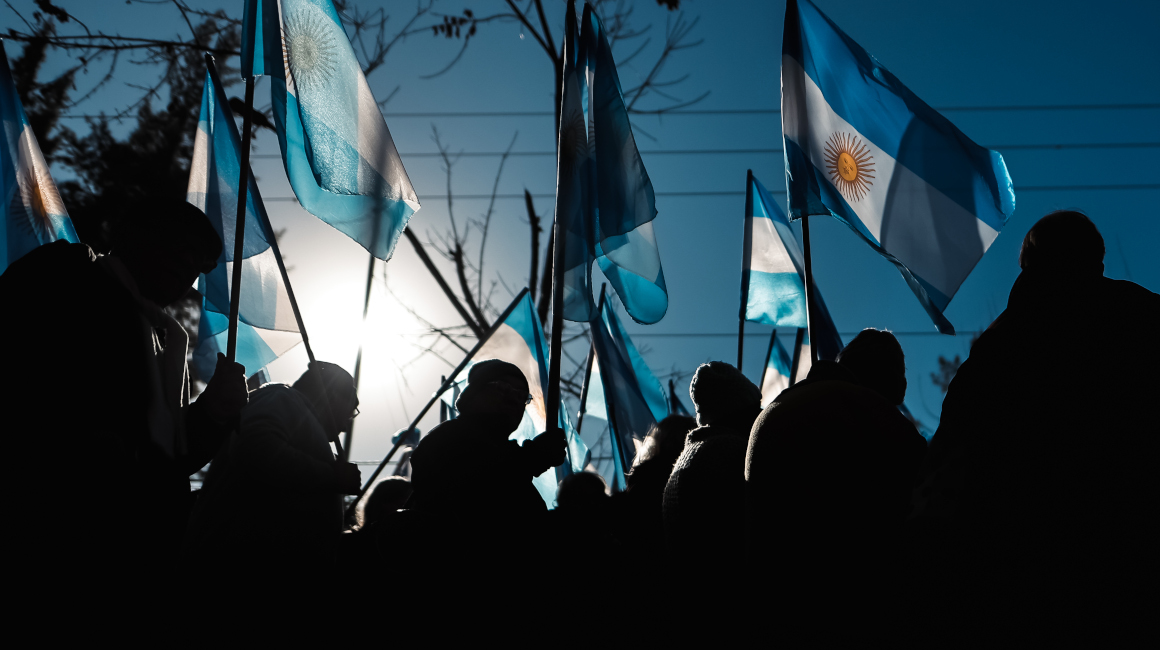 - Personas sostienen banderas de Argentina durante el discurso del gobernador de la provincia de Buenos Aires, Axel Kicillof, 1 de julio de 2024.