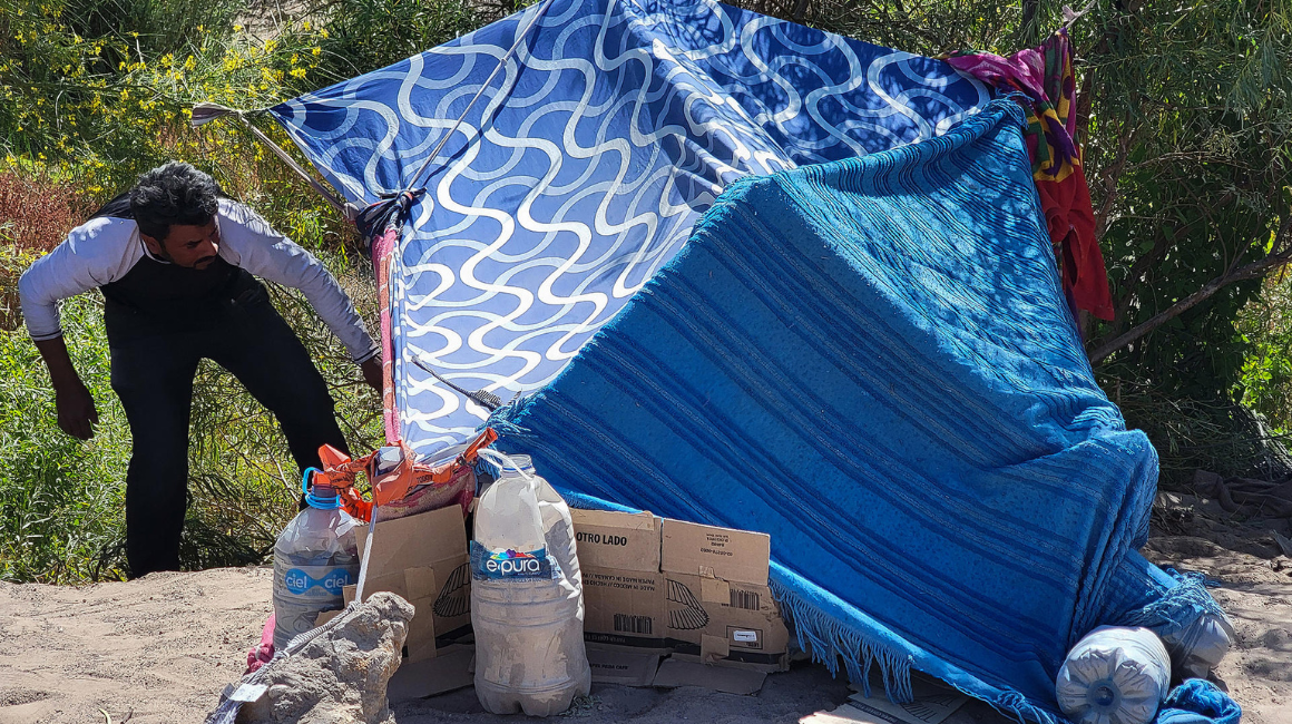 Un migrante organiza una carpa hecha por cobijas a orillas del Río Bravo, el 1 de julio de 2024 en Ciudad Juárez (México).